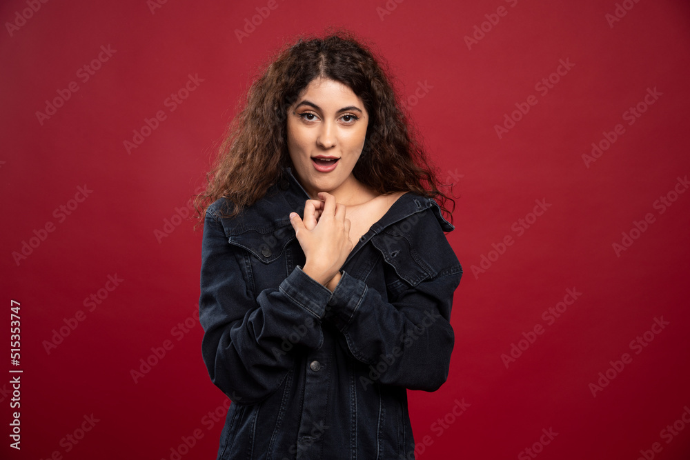 Beautiful curly woman looking at camera on red background Beautiful curly woman looking at camera on red background