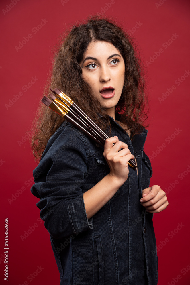 Curly painter with paintbrushes getting shocked about something Curly painter with paintbrushes getting shocked about something