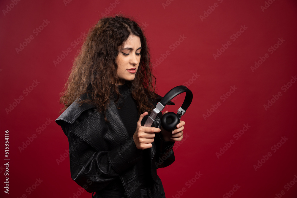 Curly woman looking at headphones on red background Curly woman looking at headphones on red background