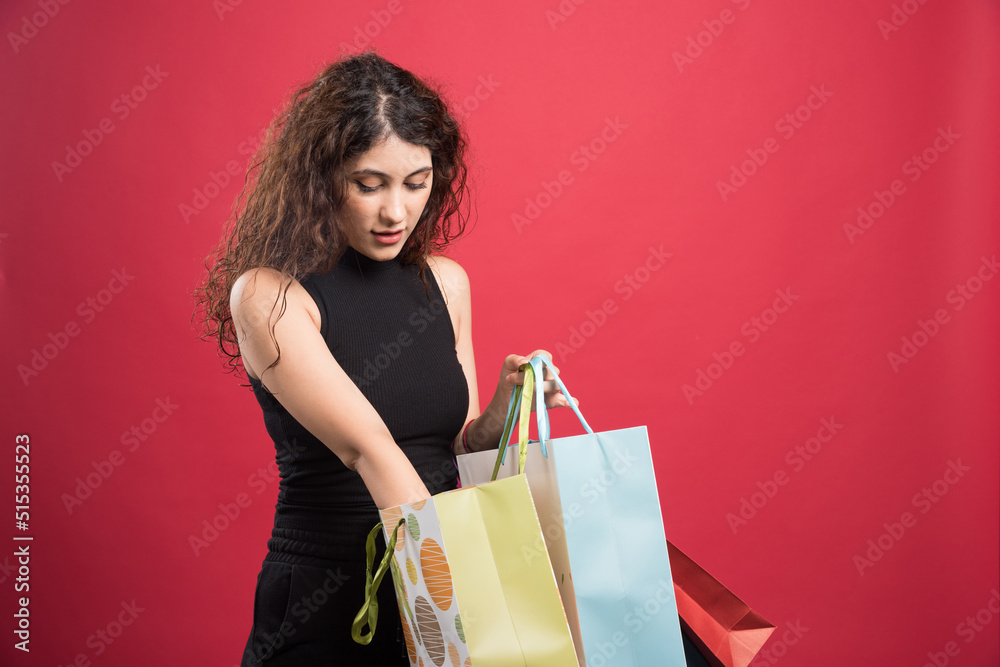 Woman showing her purchases on red background Woman showing her purchases on red background