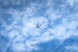 Lecący samolot na tle nieba. Błękit nieba i białe chmury.
