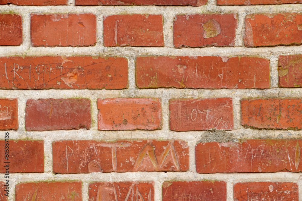 Obraz premium Carved writing on a solid red brick wall of a house or home. Closeup of rough texture and detail background with copyspace on brickwork. Modern architecture and masonry on the boundary of a building