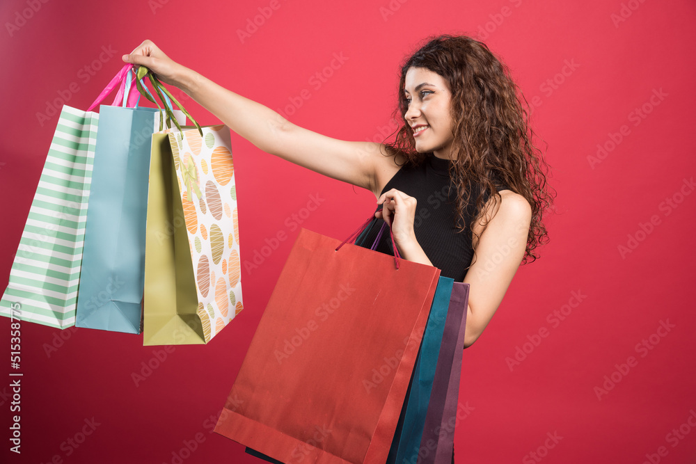 Happy woman with many of bags on red background