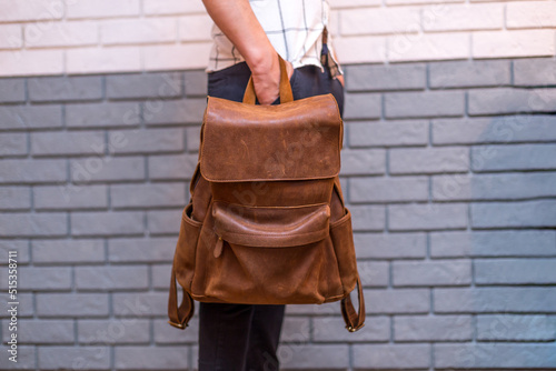 Man holding brown leather backpack in the hand