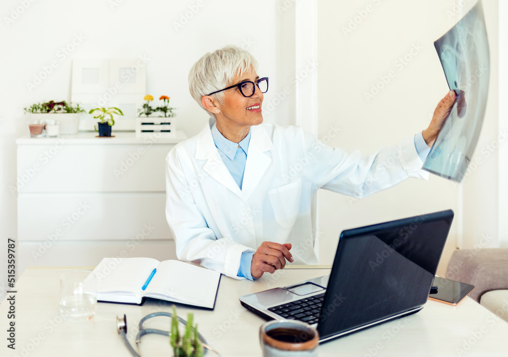 Caucasian adult female doctor looking at x-ray. Shot of a mature doctor analysing an x-ray in the office.