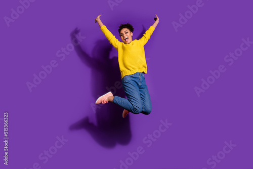 Full length photo of satisfied carefree person jumping raise fists freedom isolated on violet color background