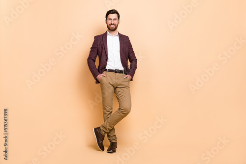 Full size image of young good looking handsome businessman hold hands in pockets isolated on beige color background