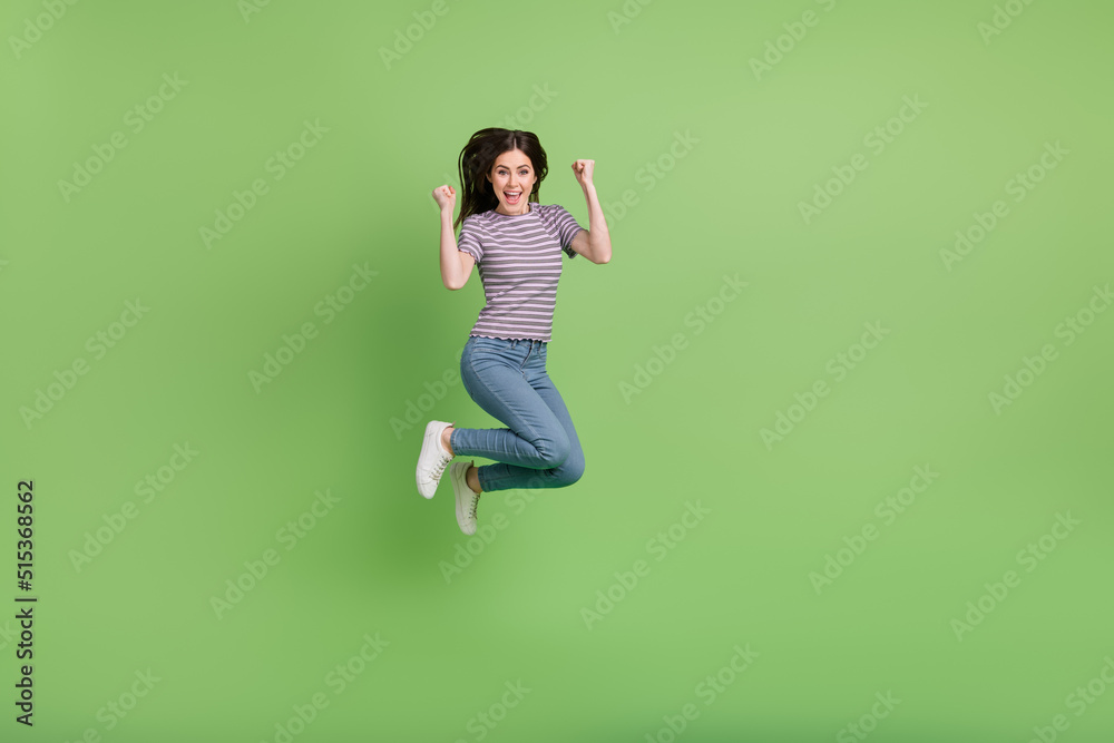 Full length body size view of attractive cheerful lucky girl jumping having fun rejoicing isolated on bright green color background Full length body size view of attractive cheerful lucky girl jumping having fun rejoicing isolated on bright green color background