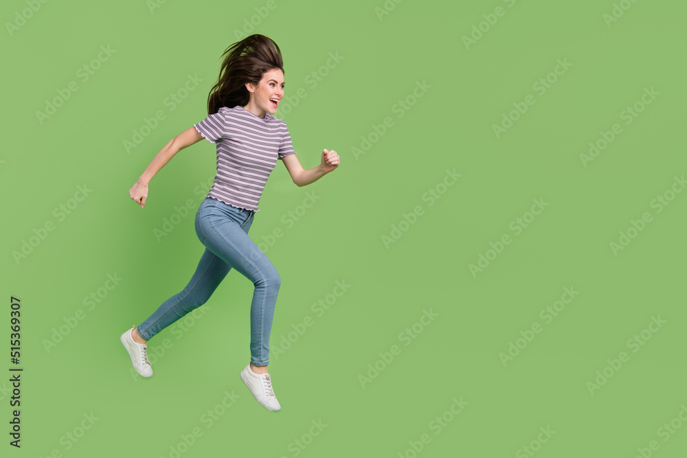 Full length body size view of attractive cheerful motivated girl jumping running copy space isolated on bright green color background Full length body size view of attractive cheerful motivated girl jumping running copy space isolated on bright green color background