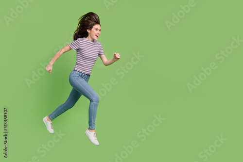 Full length body size view of attractive cheerful motivated girl jumping running copy space isolated on bright green color background