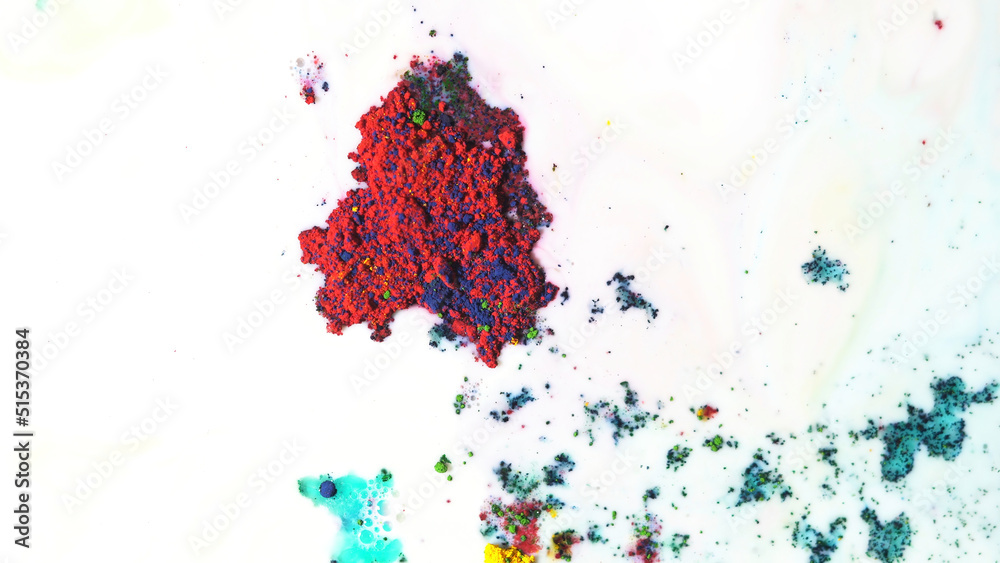 Colorful dry ink moving on white milk background, top view. Close up for powder paint floating on the surface of white liquid, art concept.