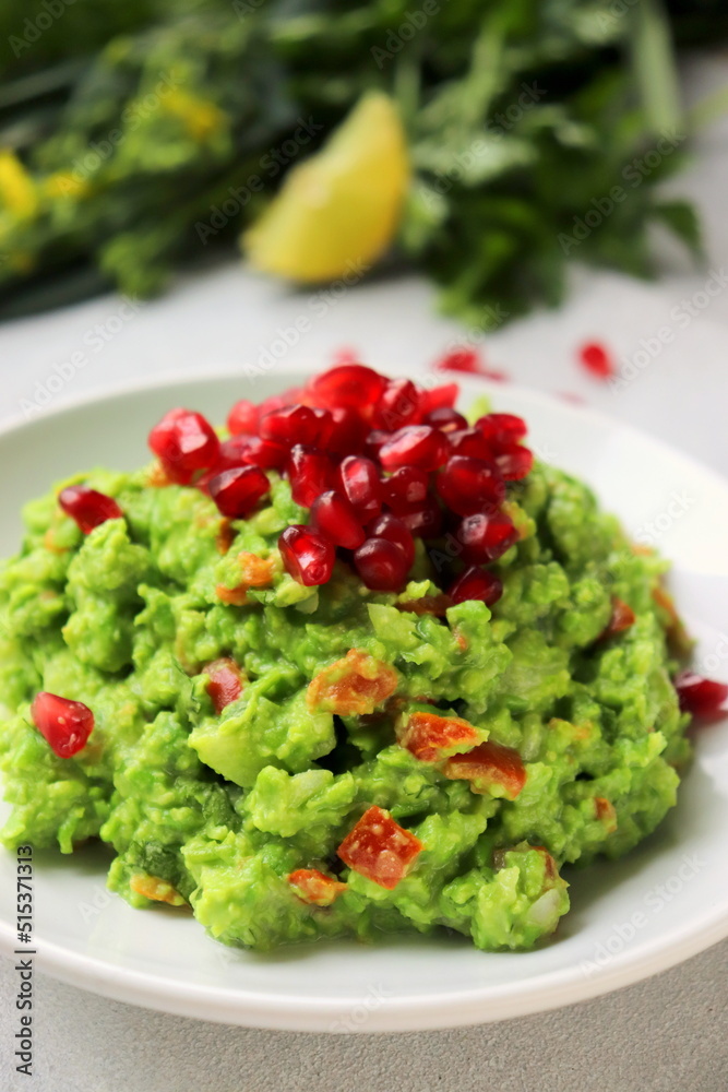 green pea guacamole with pomegranate seeds on a white plate of selective focus. green pea guacamole with pomegranate seeds on a white plate of selective focus.