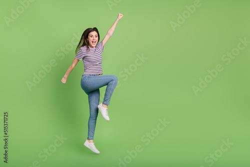 Full size photo of active energetic person raise hand fist empty space isolated on green color background
