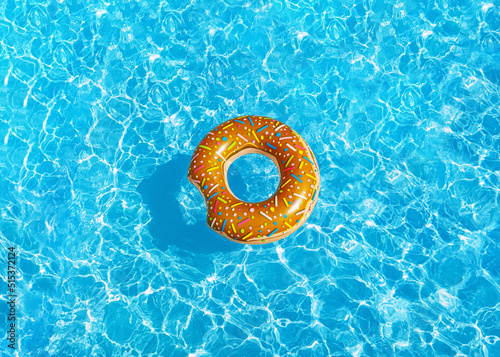 donat swimming pool ring float in blue water and sun bright. concept color summer.