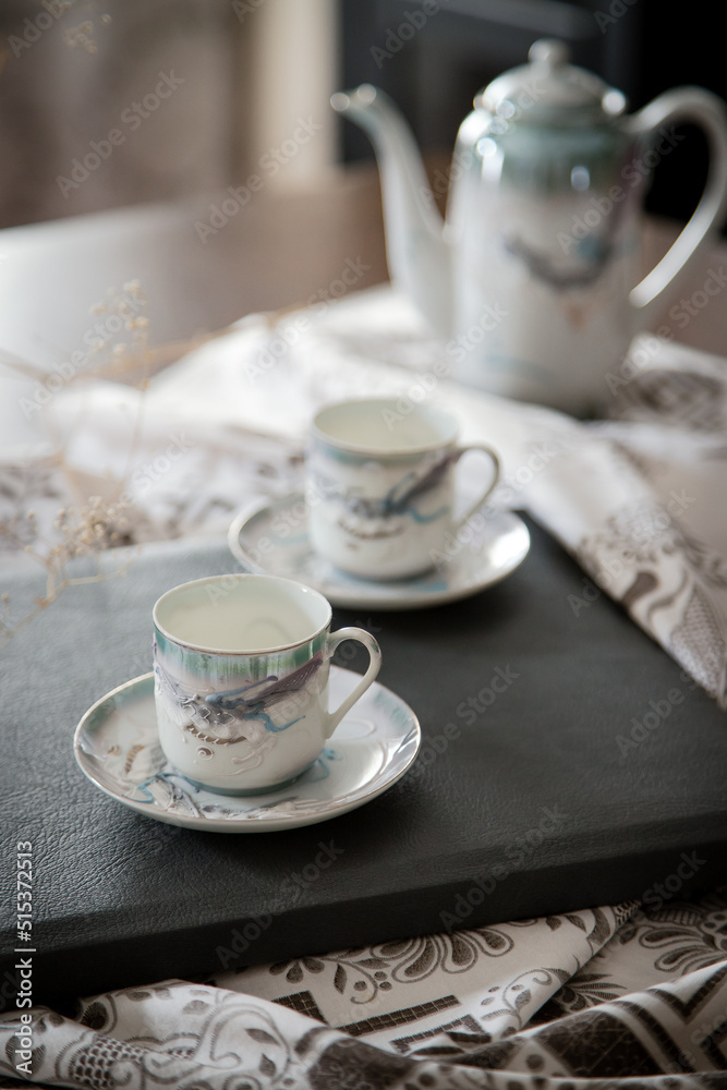 Breakfast or coffee break in a rustic, intimate and cozy atmosphere. Cups of coffee or tea crafted on an ornate table. Breakfast or coffee break in a rustic, intimate and cozy atmosphere. Cups of coffee or tea crafted on an ornate table.