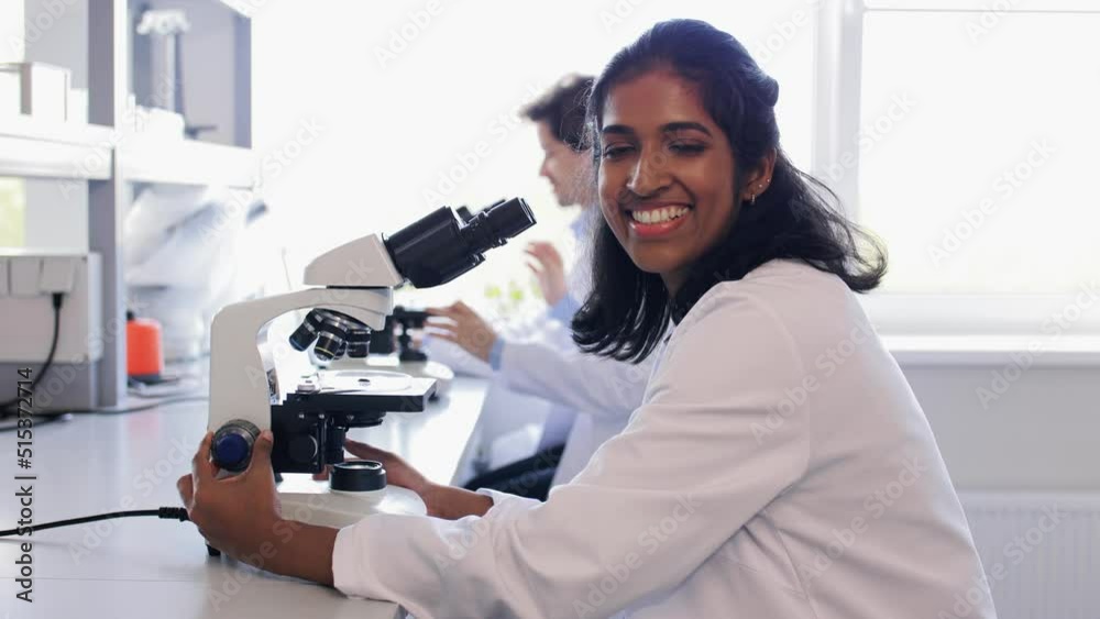 science research, work and people concept - female scientist with microscope working in laboratory