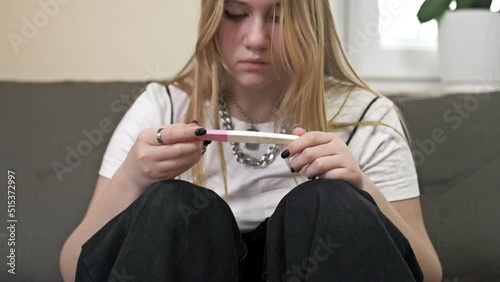 Teenage girl looks at the result of a pregnancy test and cries. The social problem.