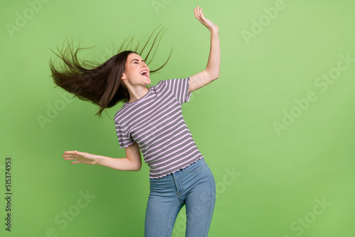 Portrait of attractive crazy cheerful brown-haired girl dancing having fun pastime isolated over bright green color background photo