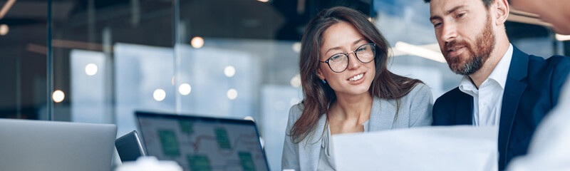 Close up of smiling businessmen discussing documents with graphs and charts in a modern office.