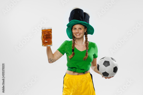 Happy excited woman in green yellow football kit holding beer mug and football ball supports favorite team. Soccer fans  competition  sport  oktoberfest concept
