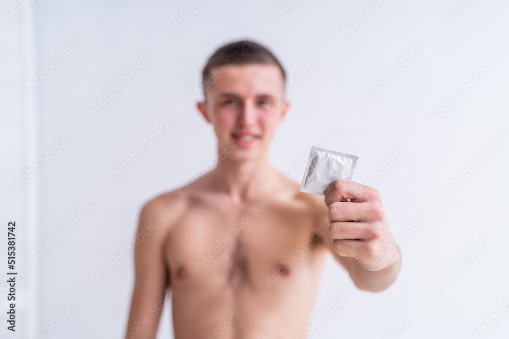 Fototapeta premium young healthy and happy man holds a condom in his hand. pulling a condom out of my jeans, the concept of safe sex. Prevents infection.