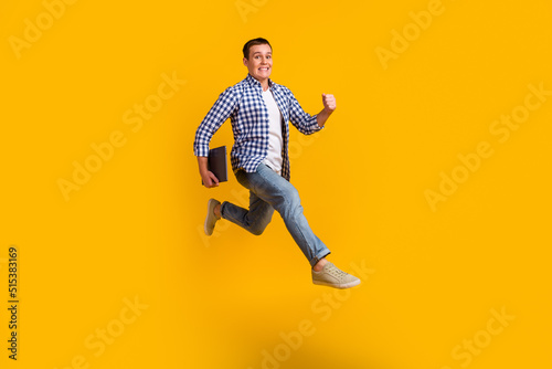 Full size photo of man jump run fast hold computer wear modern trendy outfit isolated over bright color background © Tetiana