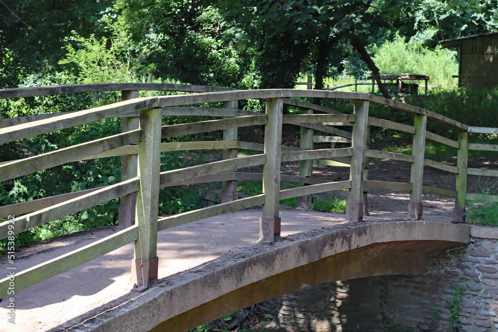 A small curved wooden bridge over the river Horner at Bossington in Somerset