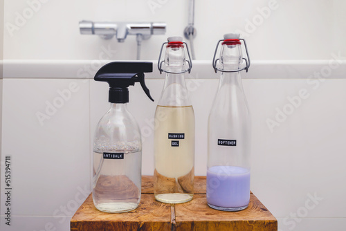 Three DIY detergent product in glass bottle with embossed black label on wooden on minimal white tile bathroom background. Eco friendly zero waste sustainable household concept. Copy space.
