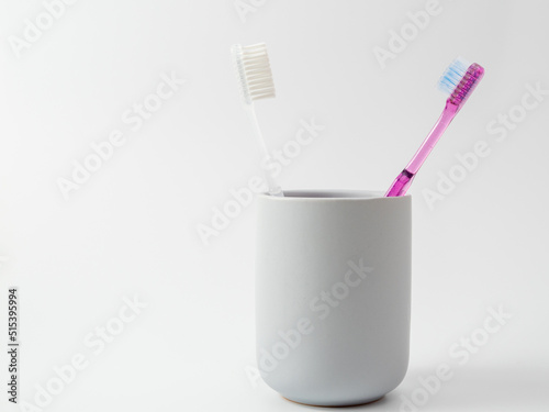 Toothbrushes in a glass with copy space on a white background