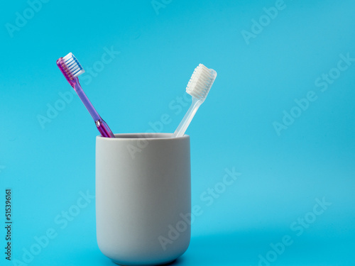 Toothbrushes in a glass with copy space on a blue background