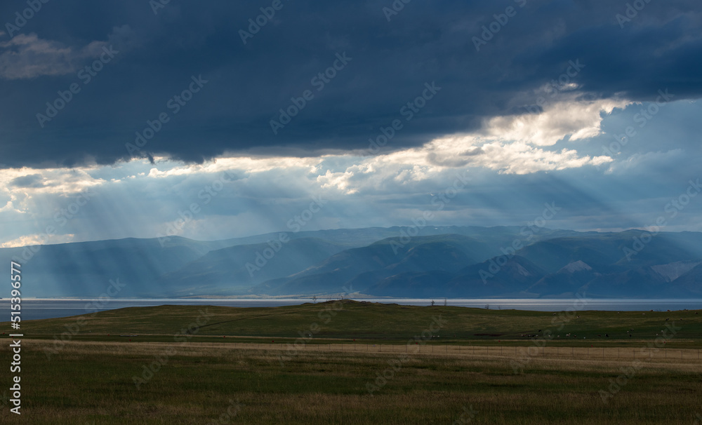 Sun rays above mountain range. Sun light through clouds. Olkhon lake. Background nature after rain. Sun rays above mountain range. Sun light through clouds. Olkhon lake. Background nature after rain.