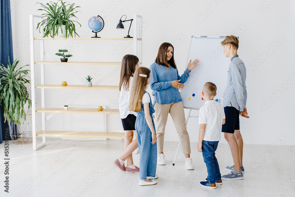 Fototapeta premium Explaining lesson and using board. Group of children students of different ages in class at school with teacher. Learning concept