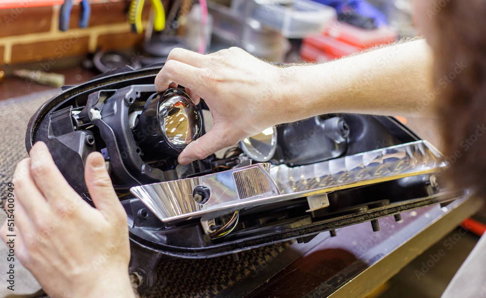 Car headlight in repair closeup. The car mechanic installs the lens in