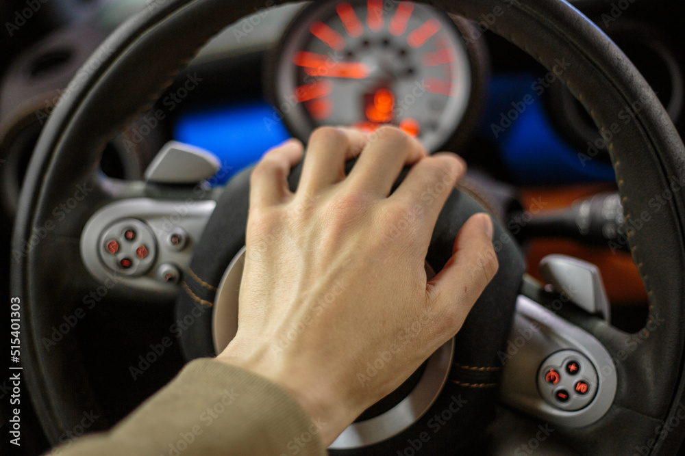 Close-up of the driver's hand on the steering wheel of the car. A man's hand on the steering wheel of a modern car close-up, selective focus. Close-up of the driver's hand on the steering wheel of the car. A man's hand on the steering wheel of a modern car close-up, selective focus.