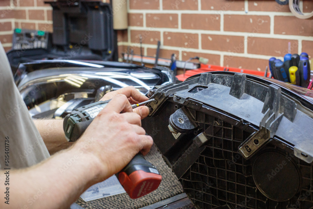 Foto de Car headlight in repair closeup. The car mechanic installs the