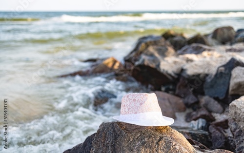 The hat lies on the stones near the sea shore under the summer setting sun