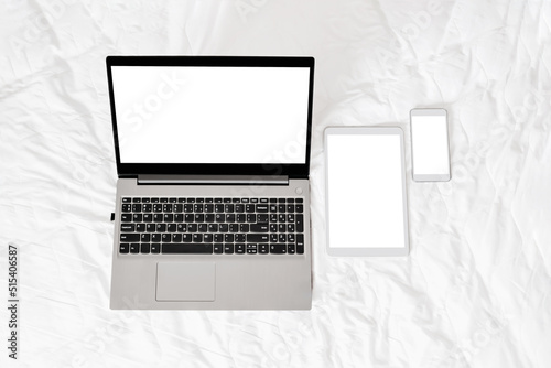 Open grey laptop with white digital tablet and smartphone on a white background