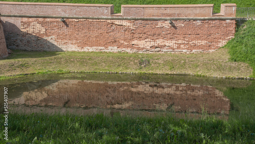 Fortress moat with water reflecting trees and castle walls. Bridge over the moat.
