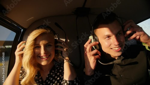 Young couple man and a blonde girl put on headphones to fly in a helicopter. photo