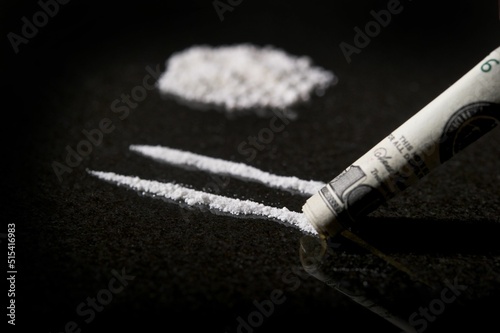 Принти на полотні Closeup shot of lines of cocaine with rolled dollar bill with a reflection on a
