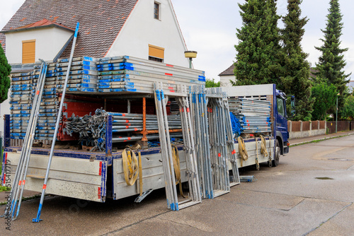 Truck with the components of scaffolding unloading in front of a residential building photo