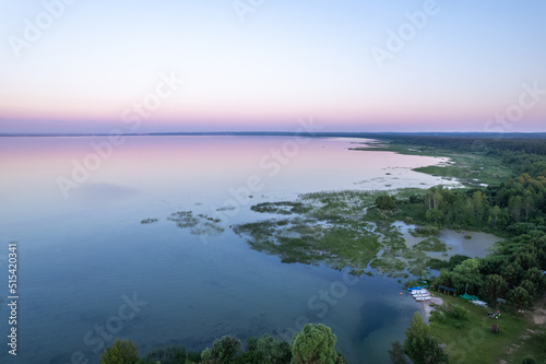 Aerial sunset view on a forest and lake with smooth mirror surface