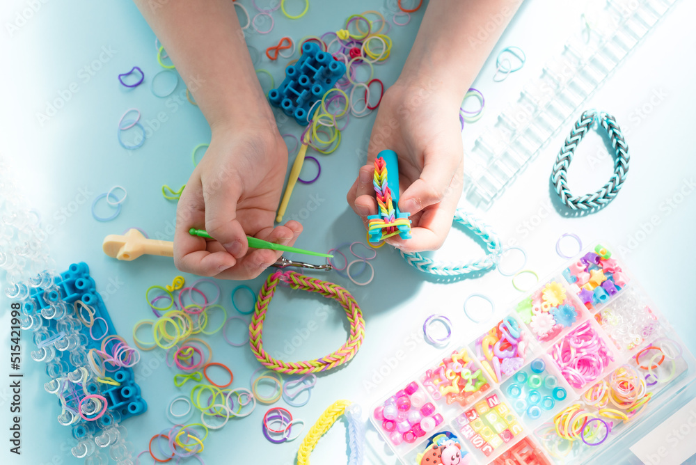 A girl makes a rainbow bracelet from rubber bands crochet. Closeup of  making decorative bracelet with elastic bands. Loom bracelets Photos |  Adobe Stock