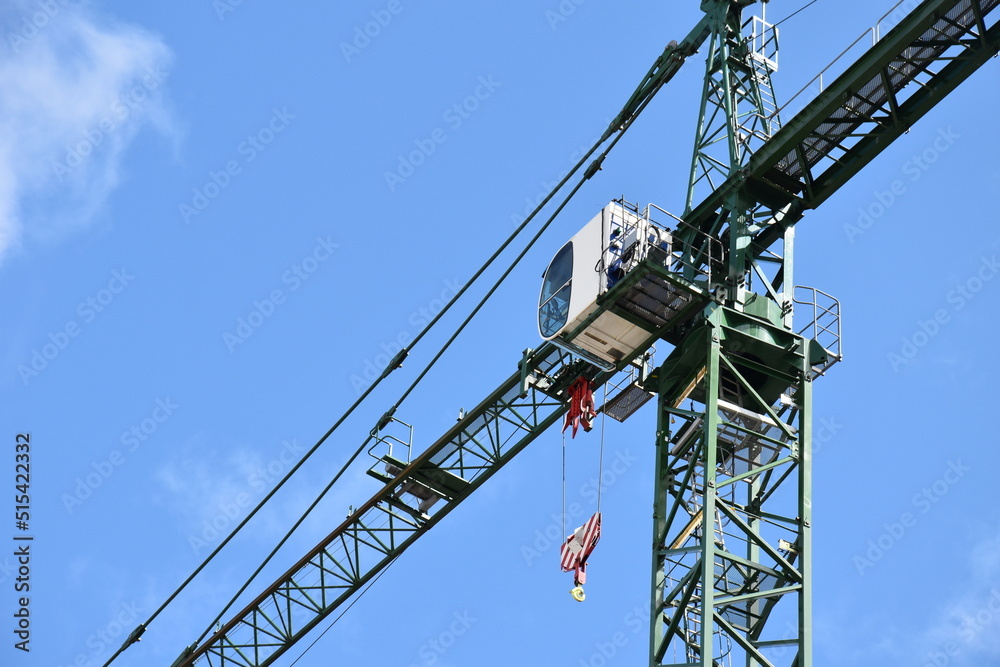 Looking up at construction cranes with a blue sky background. 