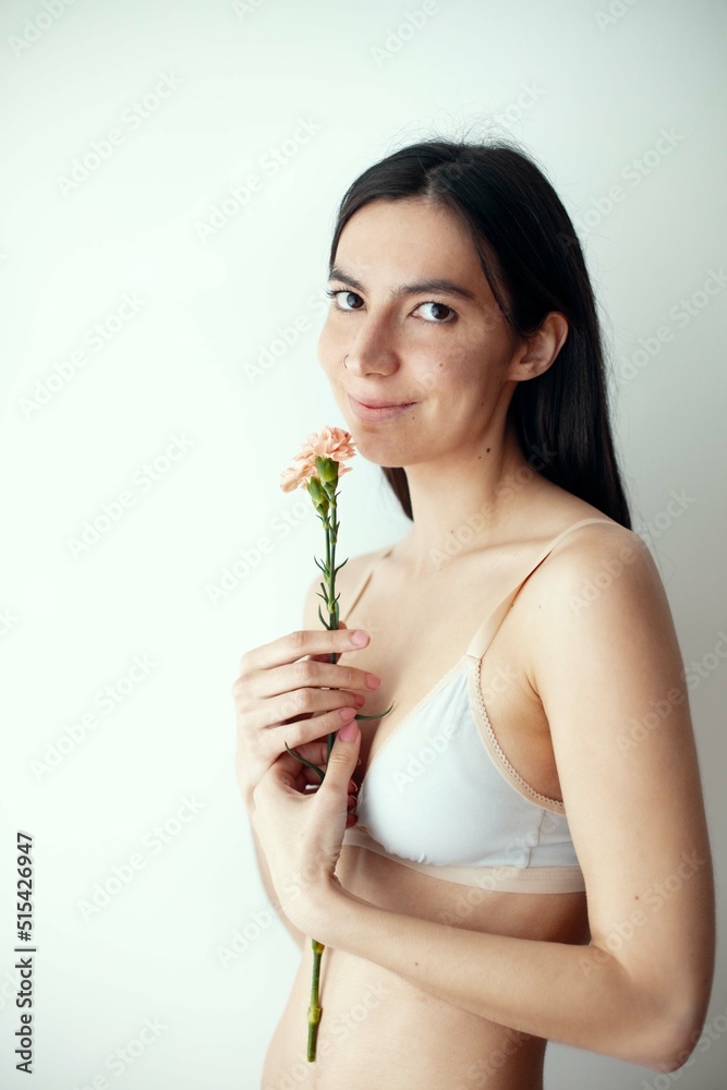 Portrait of young beautiful woman holding flower over grey background. Portrait of young beautiful woman holding flower over grey background.