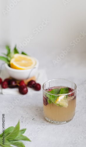 lemonade in glass on light gray concrete background. fresh summer pink drink with lemon, cherry and mint. copy space