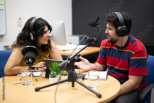 Man interviewing female guest during the live recording of a podcast or radio show. Concept of online communication and content creation.