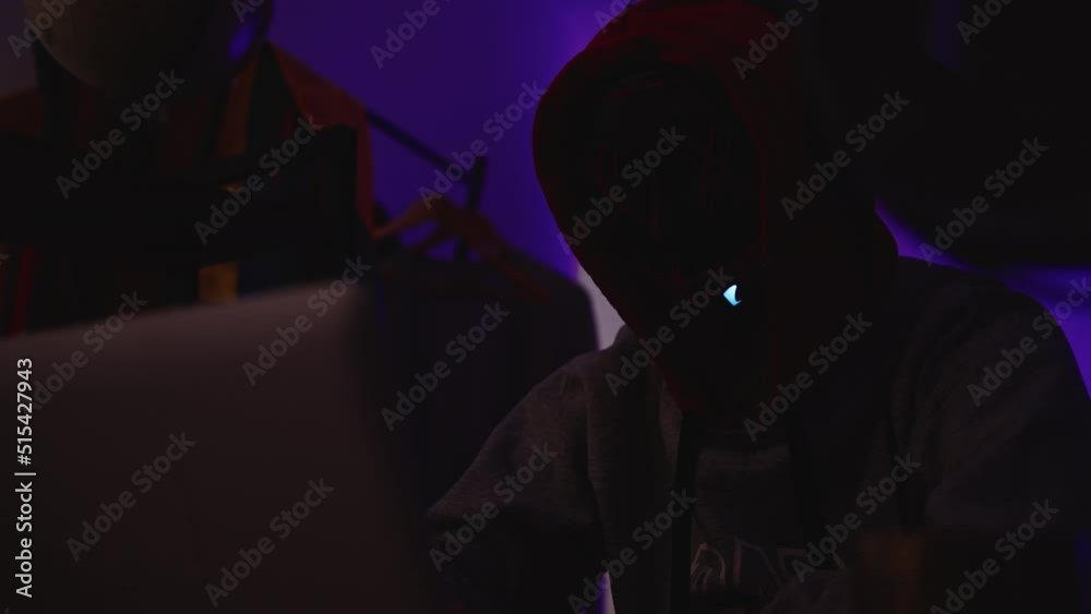 Man with a scary mask with flashing lights, anonymous hacker coding in the dark. Dark web concept Man with a scary mask with flashing lights, anonymous hacker coding in the dark. Dark web concept