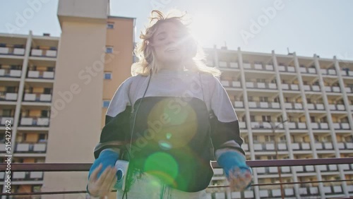 School girl, a student with a backpack in sport wear listening music on the morning sun in the city photo