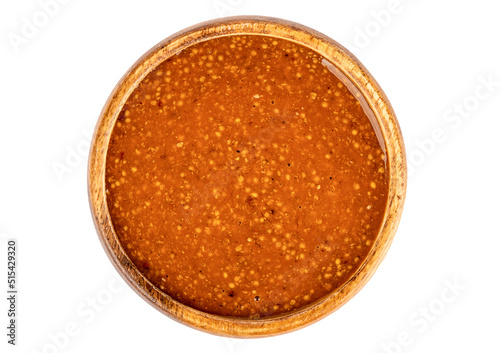 Top view of a wooden bowl full of Bavarian mustard on a white background.
